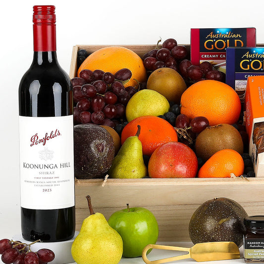 Gourmet gift basket with fruits, wine, and snacks on a white background