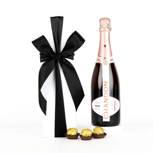 Chandon Rose champagne bottle with a black and white bow and Ferrero Rocher chocolates on a white background