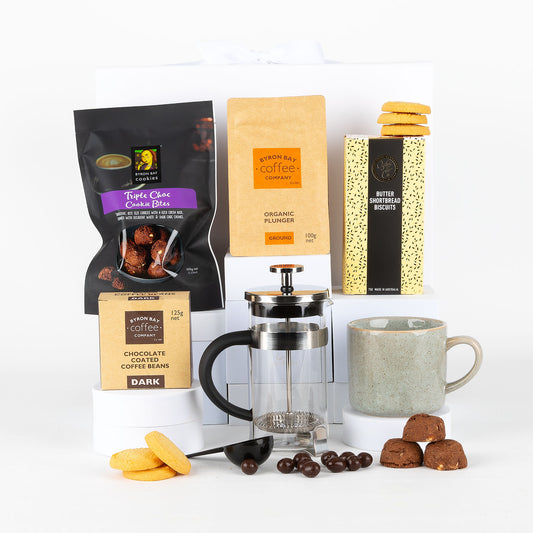 Collection of coffee products including mug, plunger, and cookies on a white background