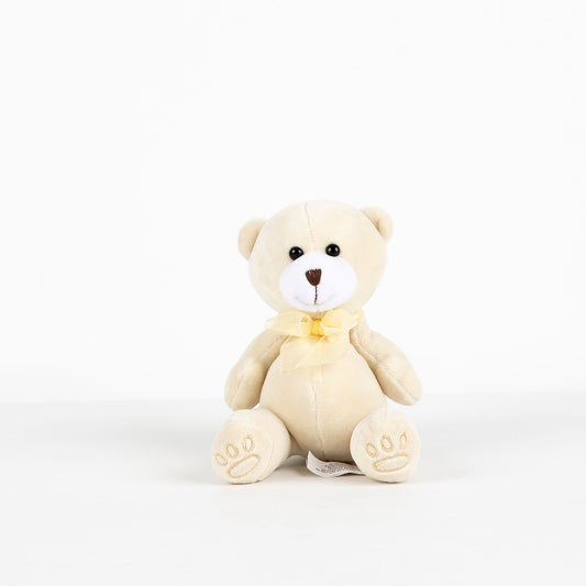 Cream-colored teddy bear with a yellow bow on a white background