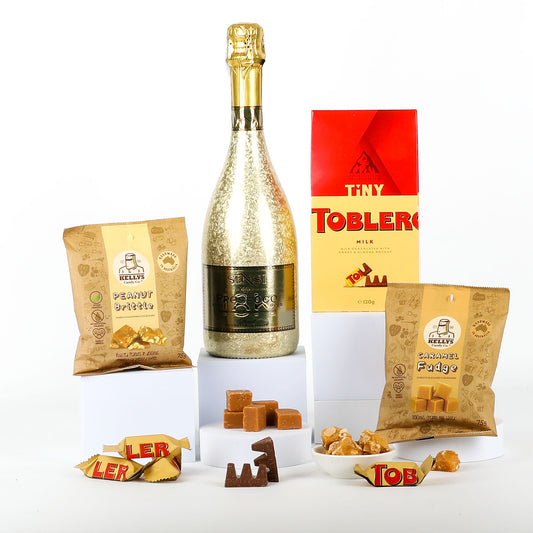Bottle of gold Prosecco, Toblerone chocolate, and snacks on a white background