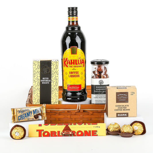 Kahlua coffee liqueur bottle with assorted chocolates and biscuits on a white background