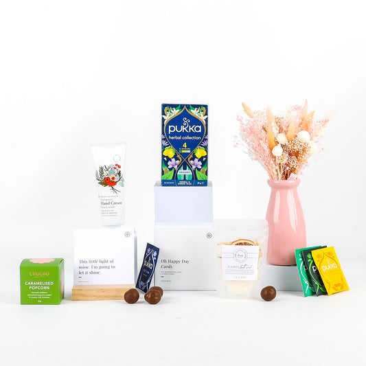 Collection including Pukka tea box, a vase with flowers, and other small items on a white background