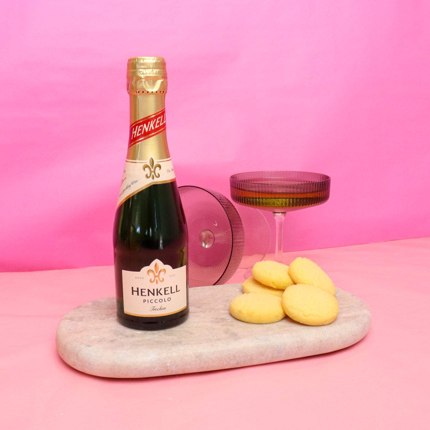 Henkel Piccolo bottle with cookies on a pink background
