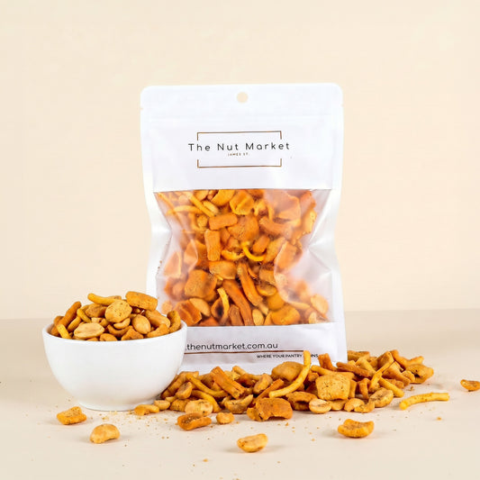 Dried snacks in a white bowl and packaging with 'The Nut Market' branding on a beige background