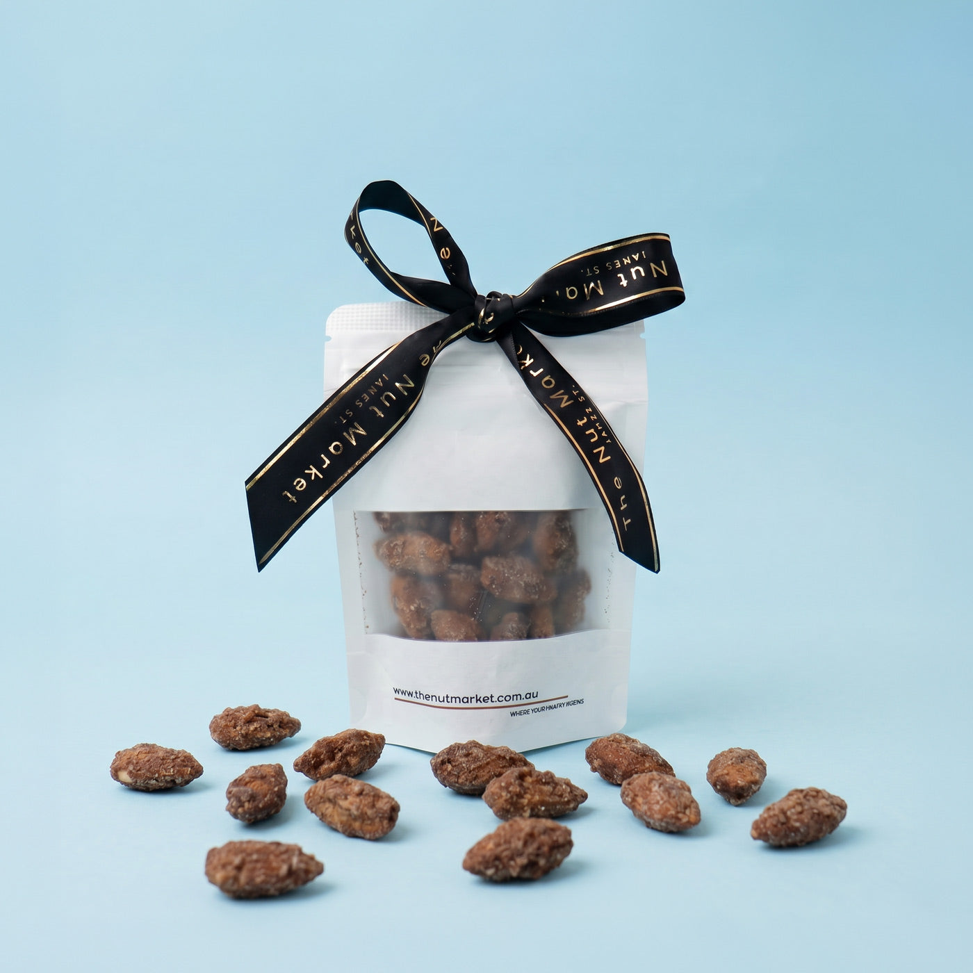 Packet of cinnamon almonds with a black ribbon on a light blue background