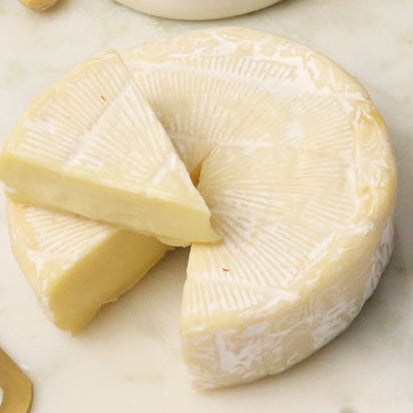 Assorted cheese, crackers, nuts, and jam on a marble board with a knife.