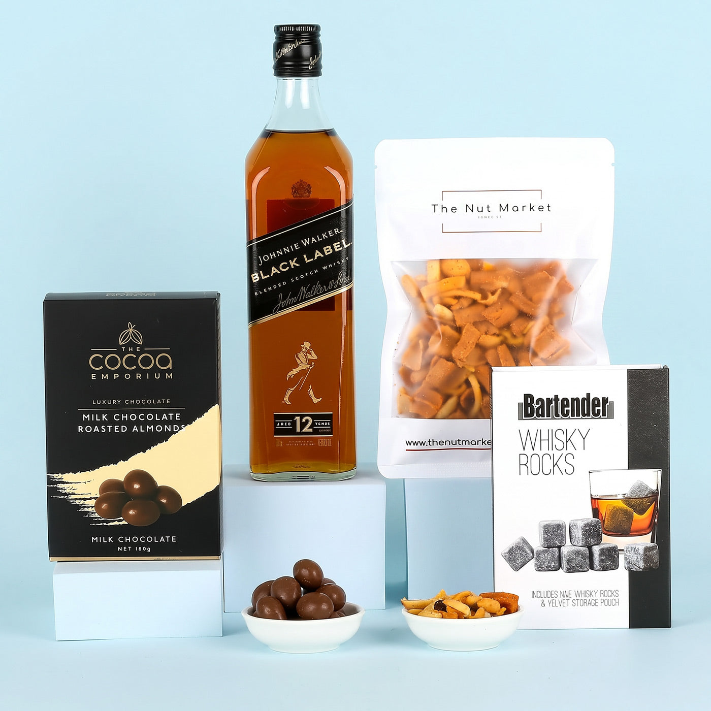 Johnnie Walker Black Label whisky with snacks and chocolate on a light blue background
