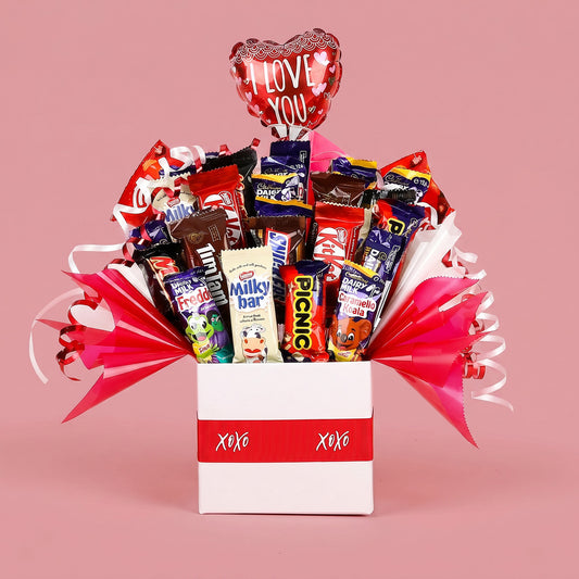 Bouquet of candy bars in a box with 'I Love You' balloon on a pink background