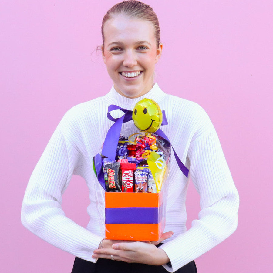 Person holding a gift basket with a pink background