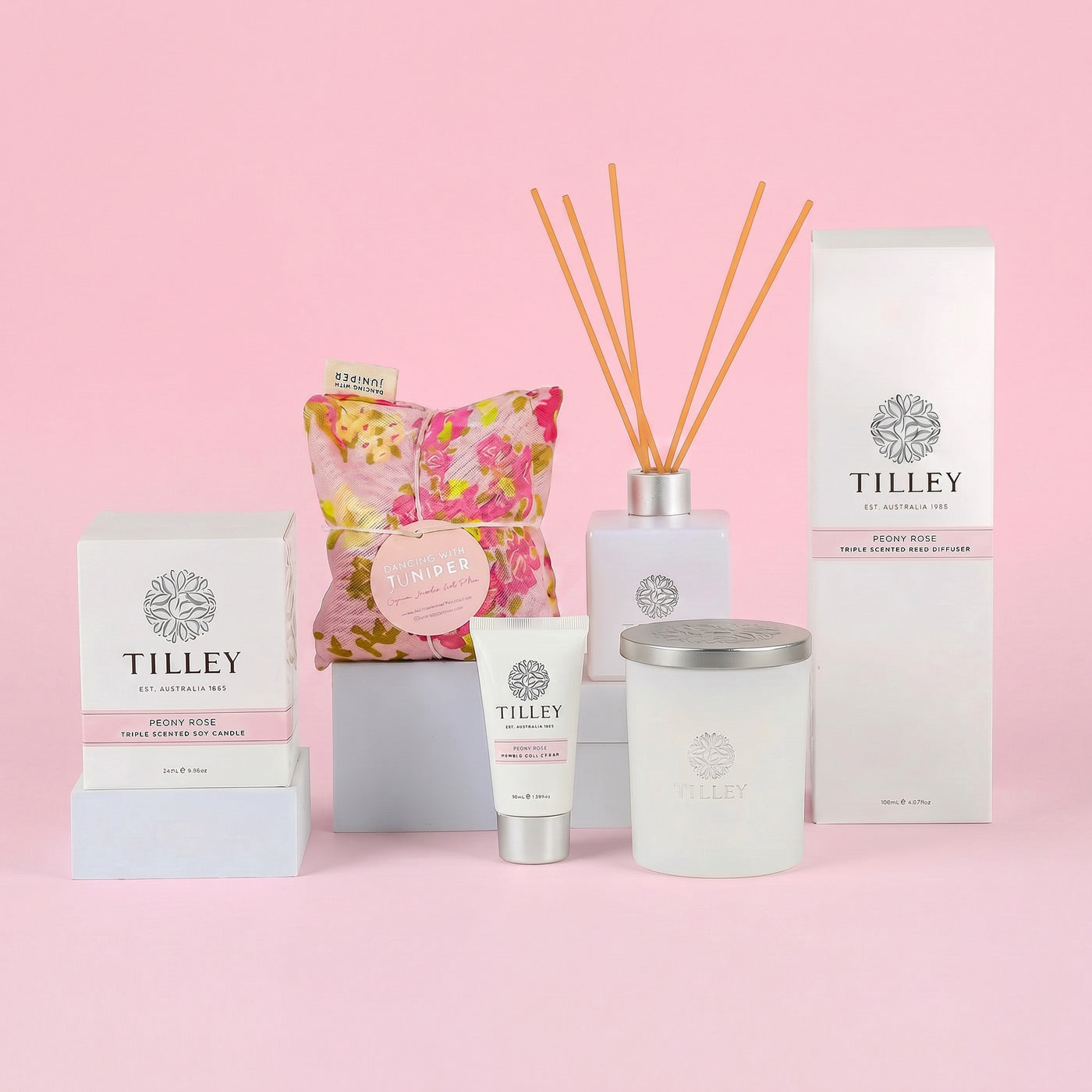 Tilley products including candles, diffuser, and packaging on a pink background