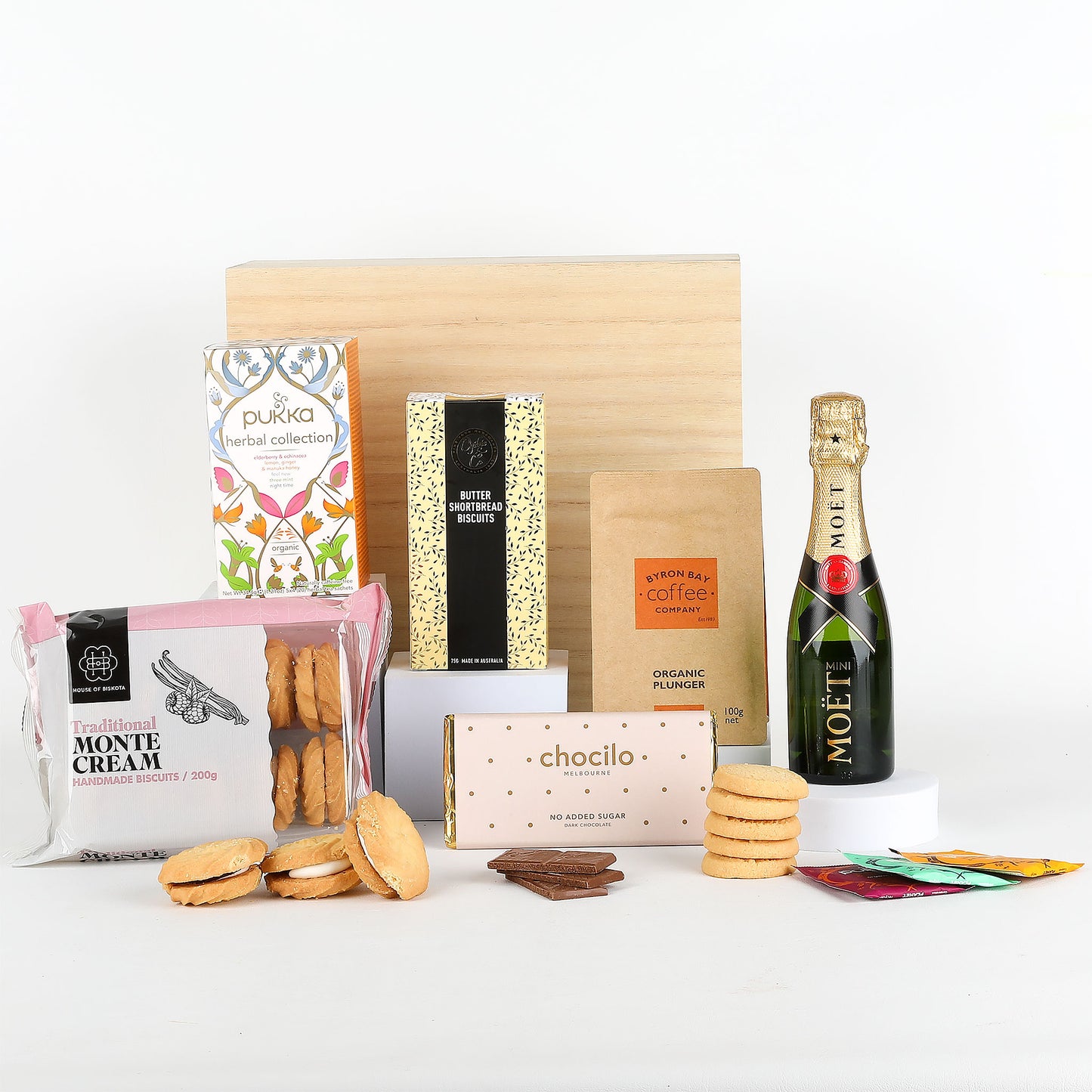 Gourmet gift box with snacks, tea, and a bottle of champagne on a white background