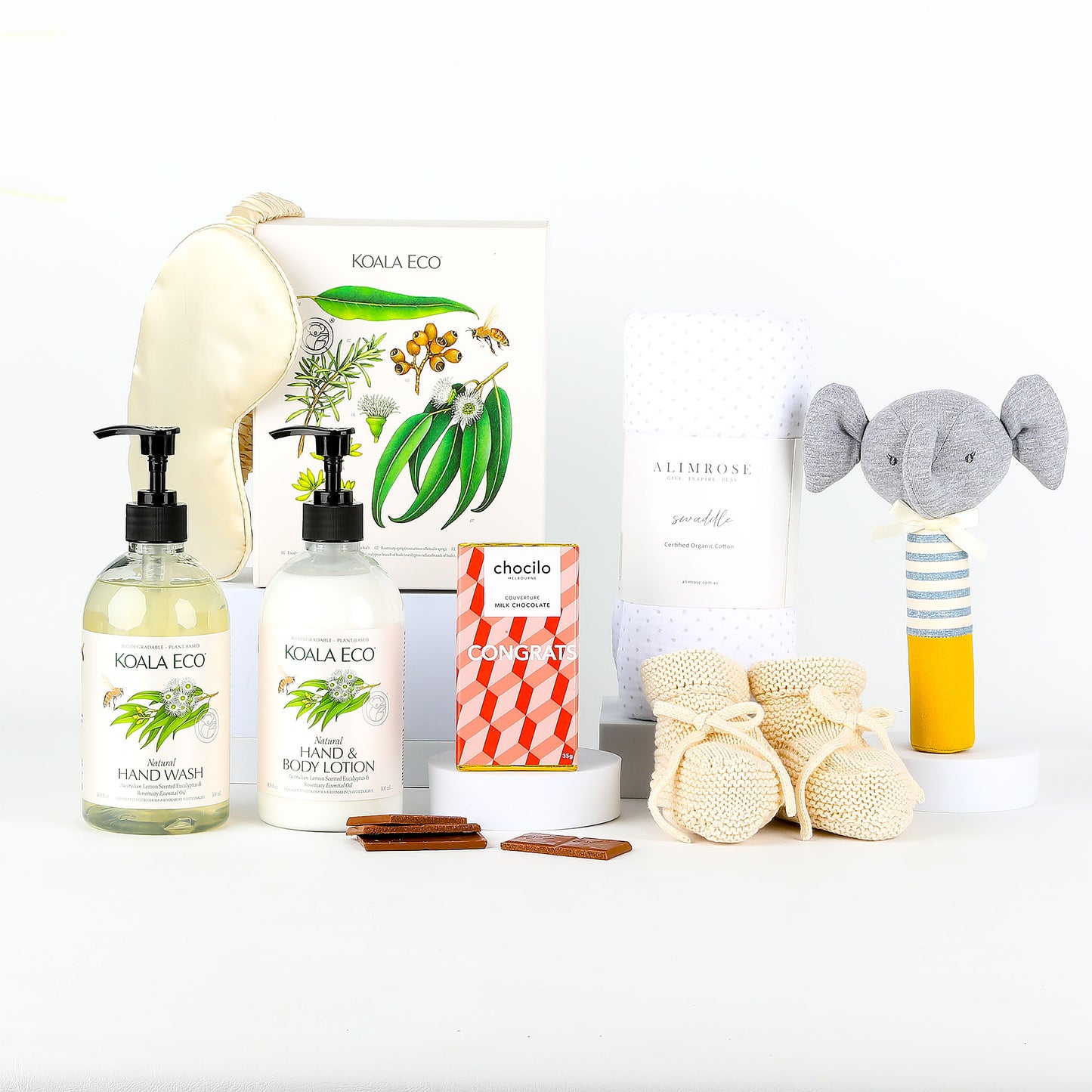Collection of eco-friendly baby products including bottles of hand wash & lotion, booties and a toy on a white background