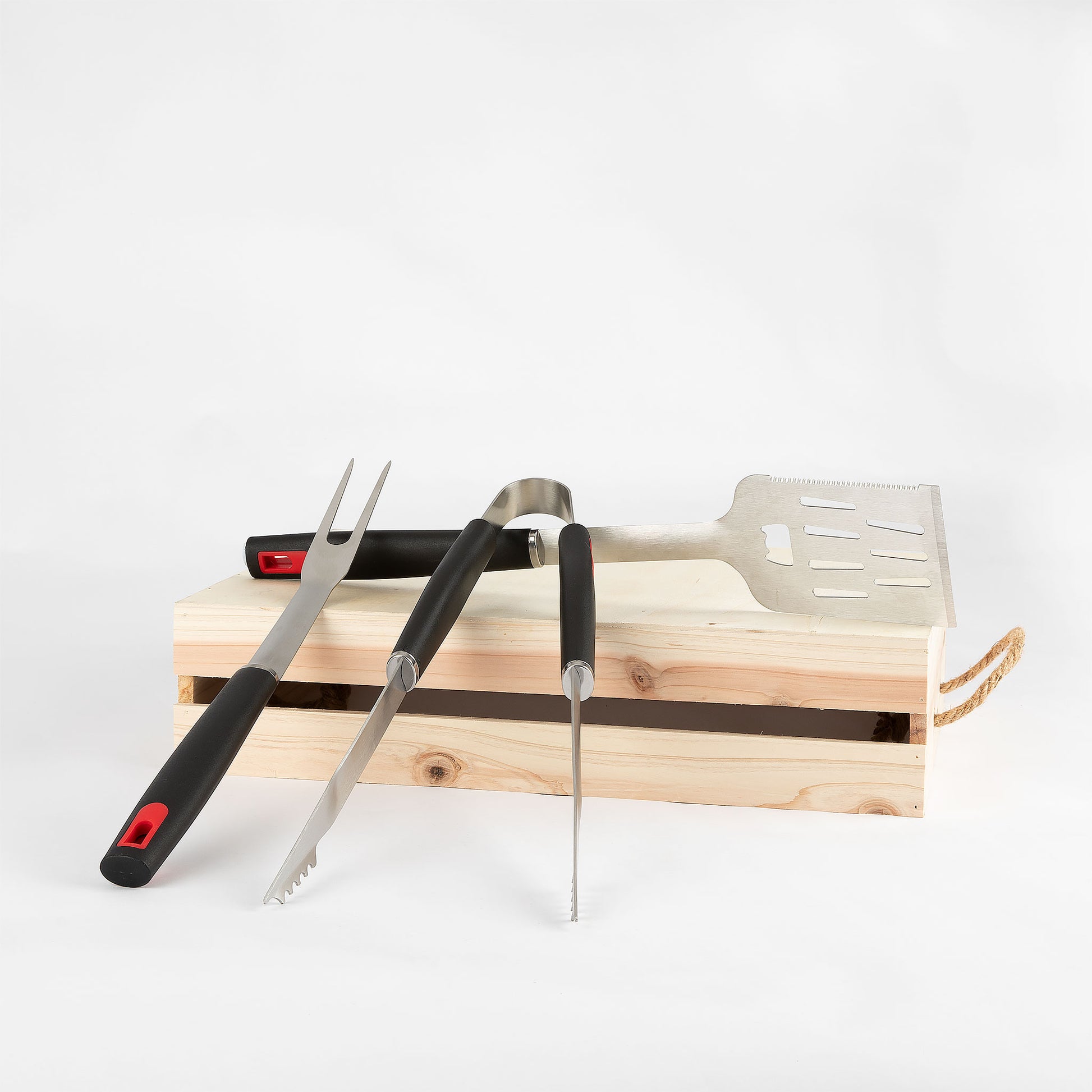 Set of barbecue tools including a fork, tongs, and spatula on a wooden stand with a white background.
