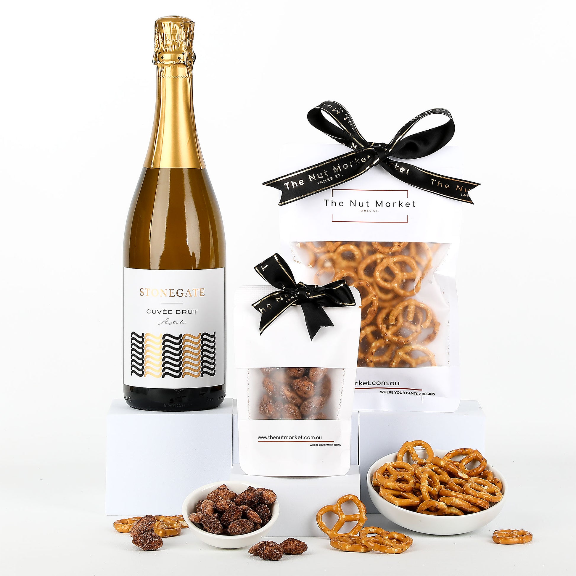 Bottle of wine, a packet of pretzels and a packet of cinnamon almonds on a white background