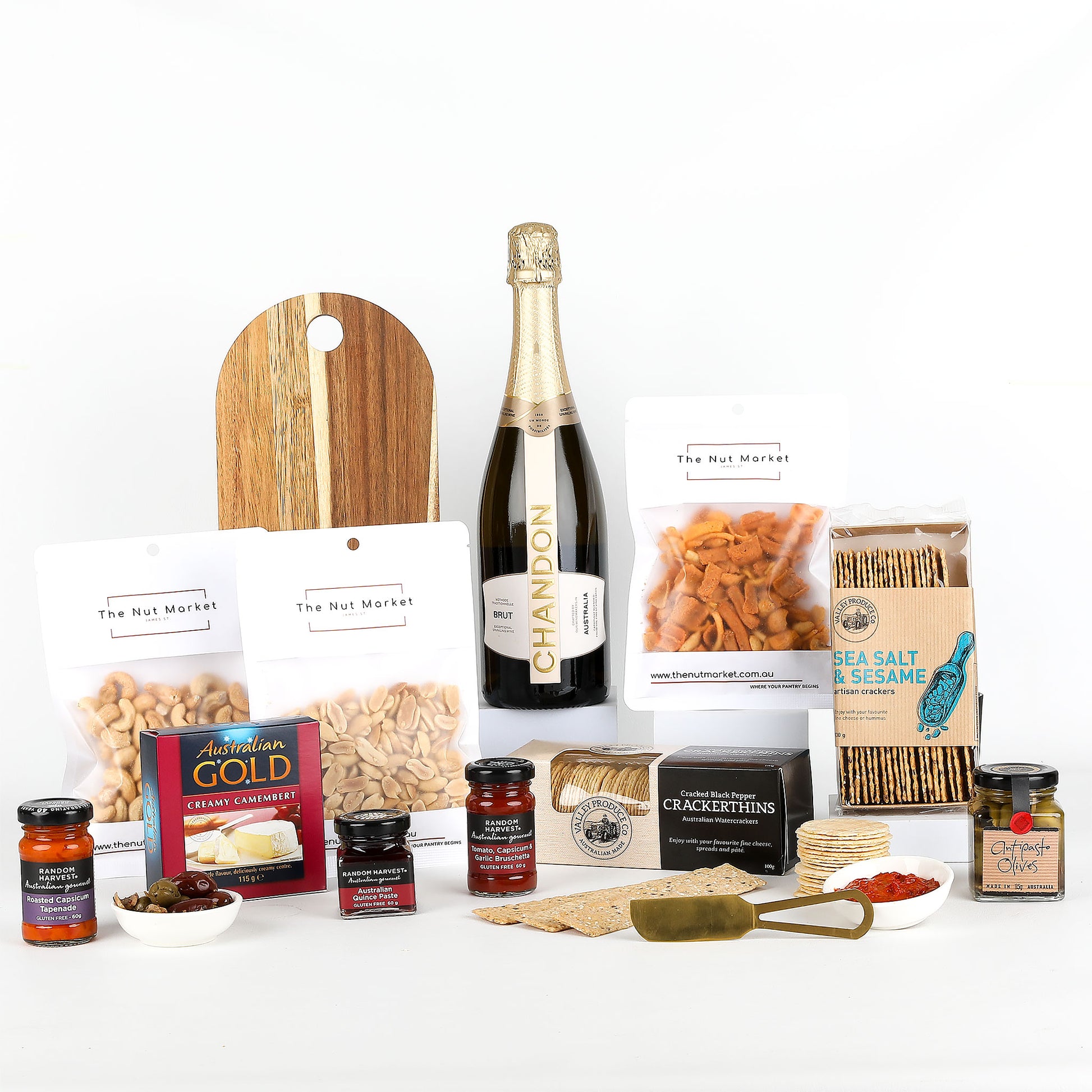 Assorted food items including bottle of Chandon, nuts, spreads & cheese board on a white background