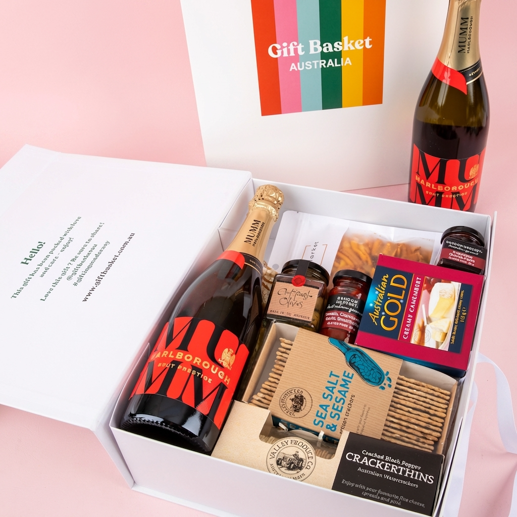 Gift basket with champagne, snacks, and a card on a pink background
