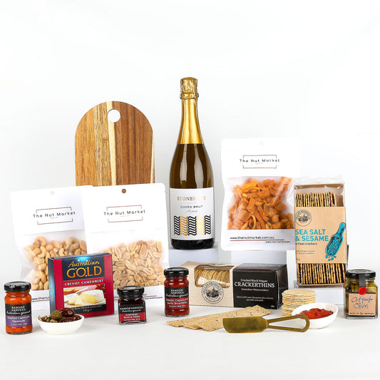 Assorted food items including wine, nuts, spreads & cheese board on a white background