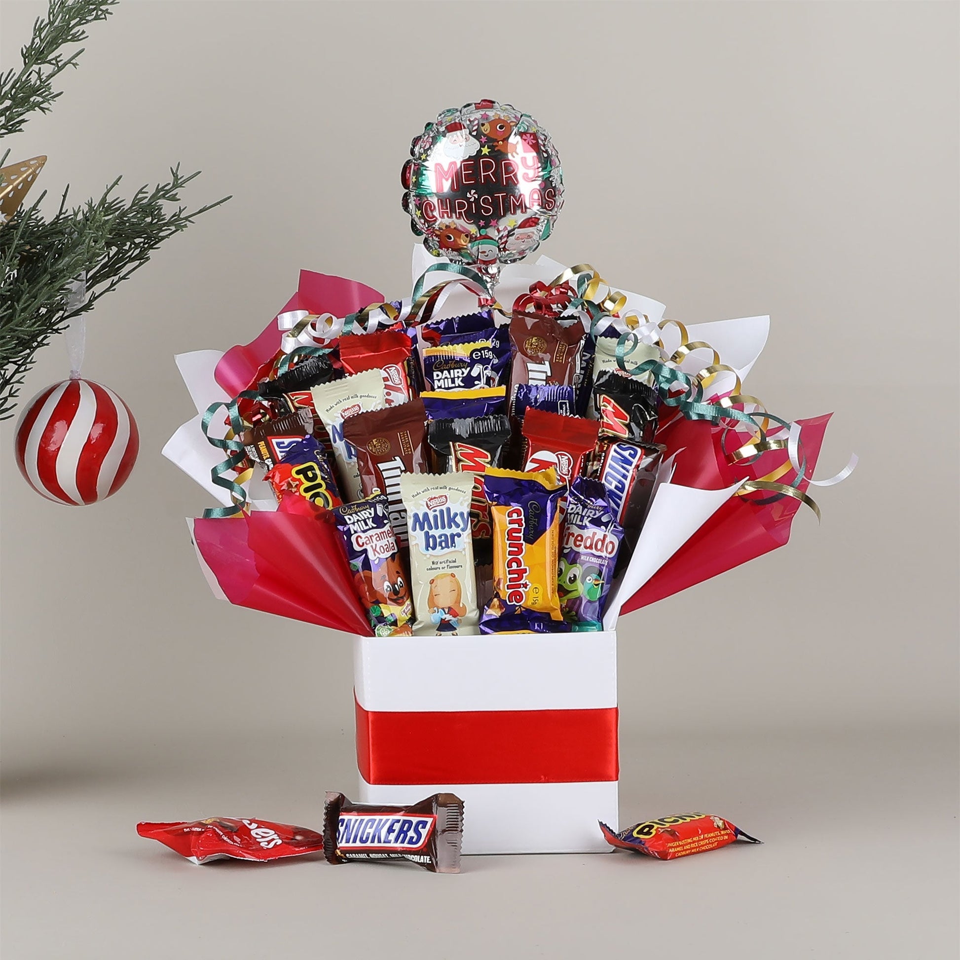 Assorted chocolate bouquet with a 'Merry Christmas' balloon against a neutral background.