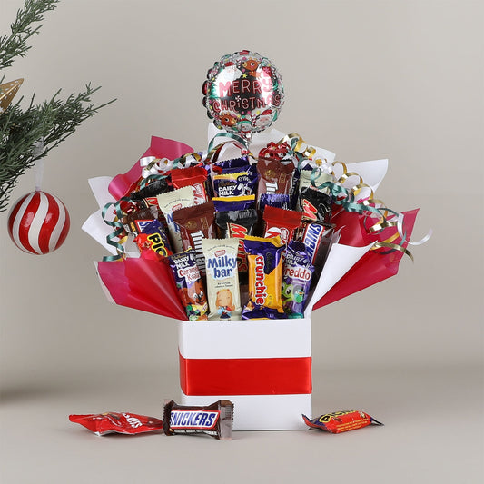 Assorted chocolate bouquet with a 'Merry Christmas' balloon against a neutral background.
