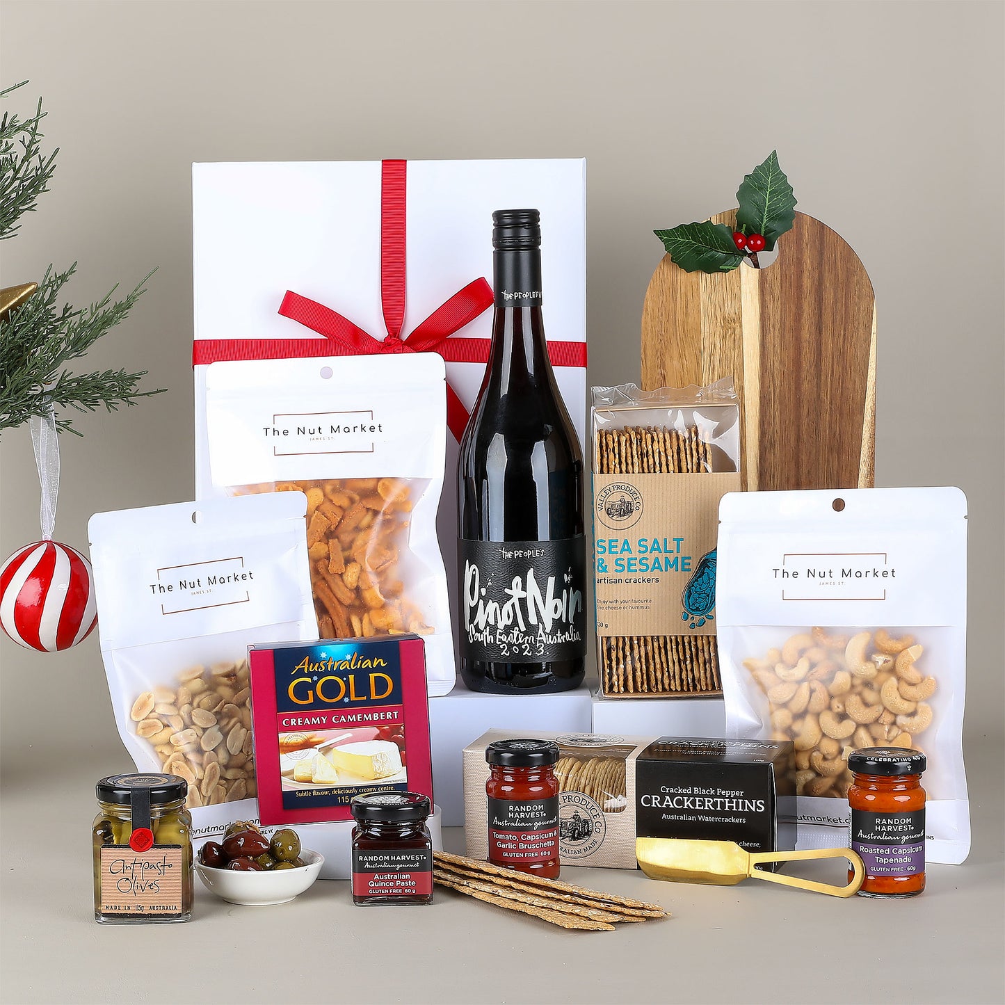 Gourmet gift hamper which includes wine, snacks, and spreads on a neutral background