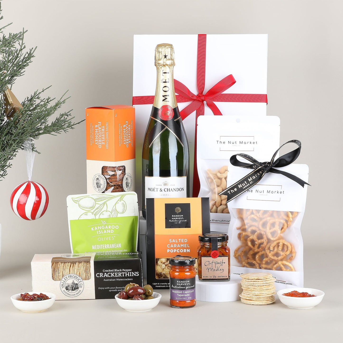Gourmet gift basket with champagne, snacks, and other treats on a neutral background