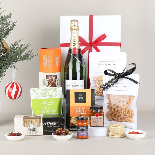 Gourmet gift basket with champagne, snacks, and other treats on a neutral background