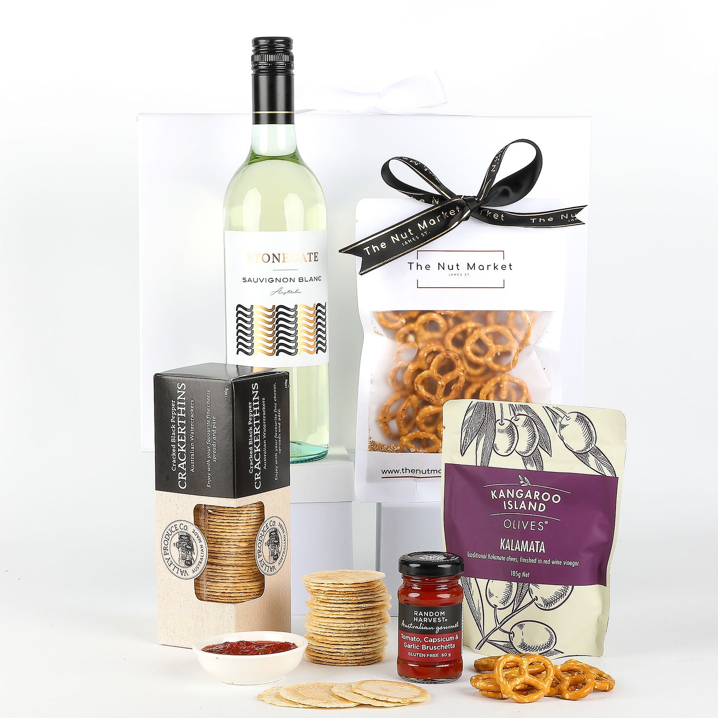 Gift set with wine, crackers, relish, and pretzels on a white background