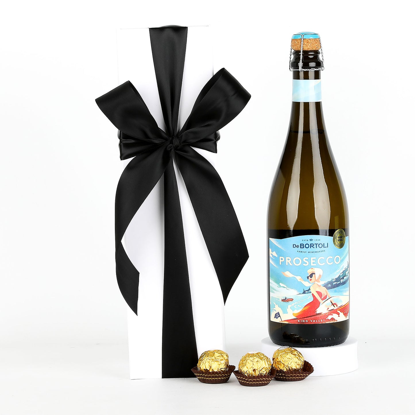 Bottle of De Bortoli Prosecco with a black ribbon and Ferrero Rocher chocolates on a white background