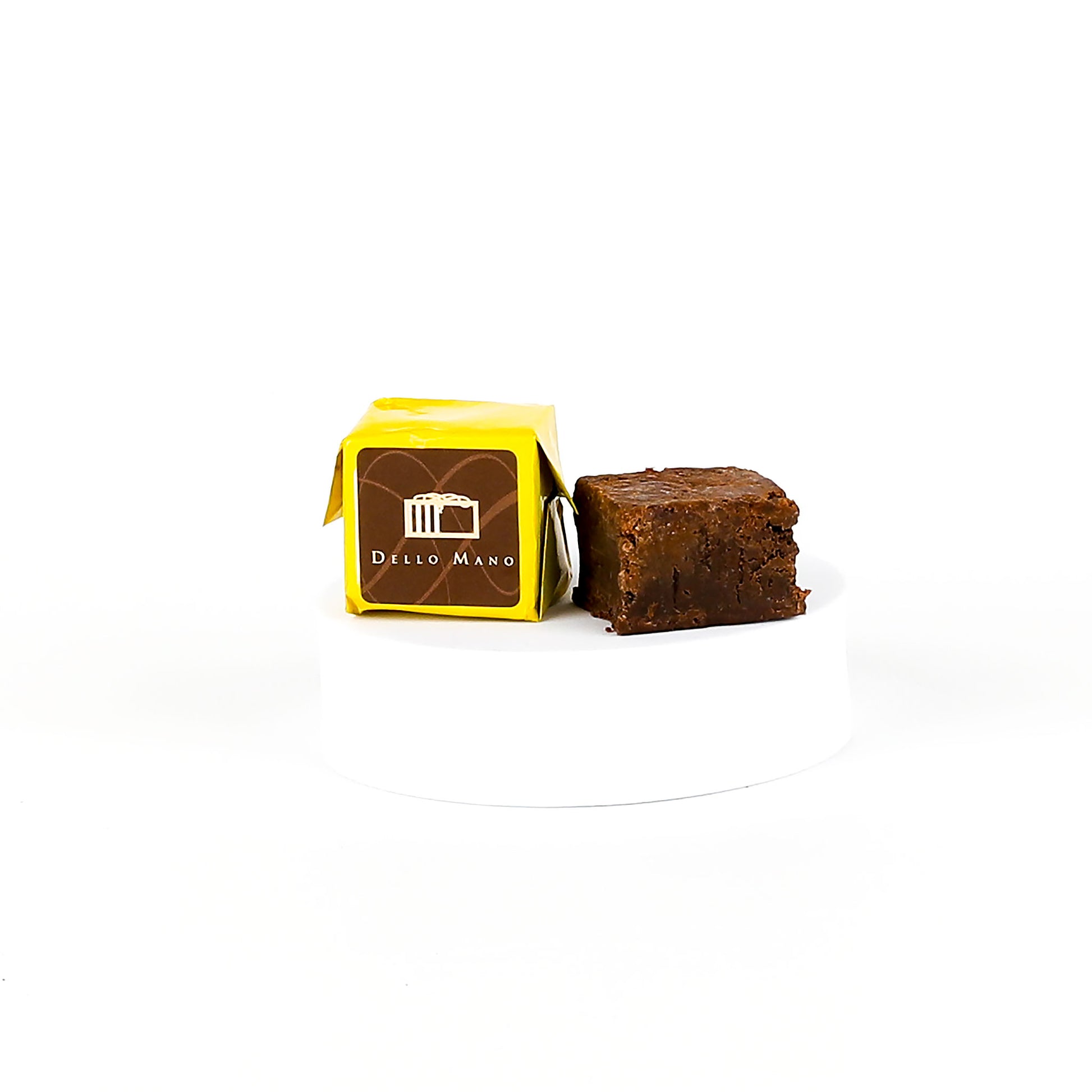 Brownie next to a yellow packaging box with 'Dello Mano' branding on a white background