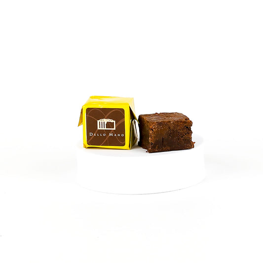 Brownie next to a yellow packaging box with 'Dello Mano' branding on a white background