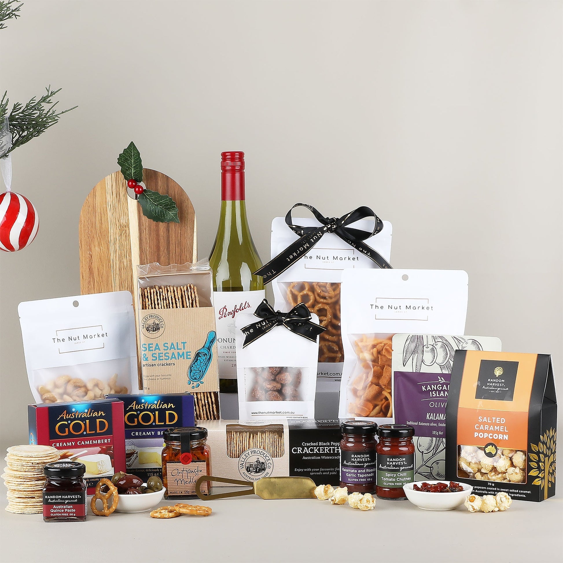 Assorted gourmet food items including a bottle of wine, crackers, and various packaged snacks on a neutral background.