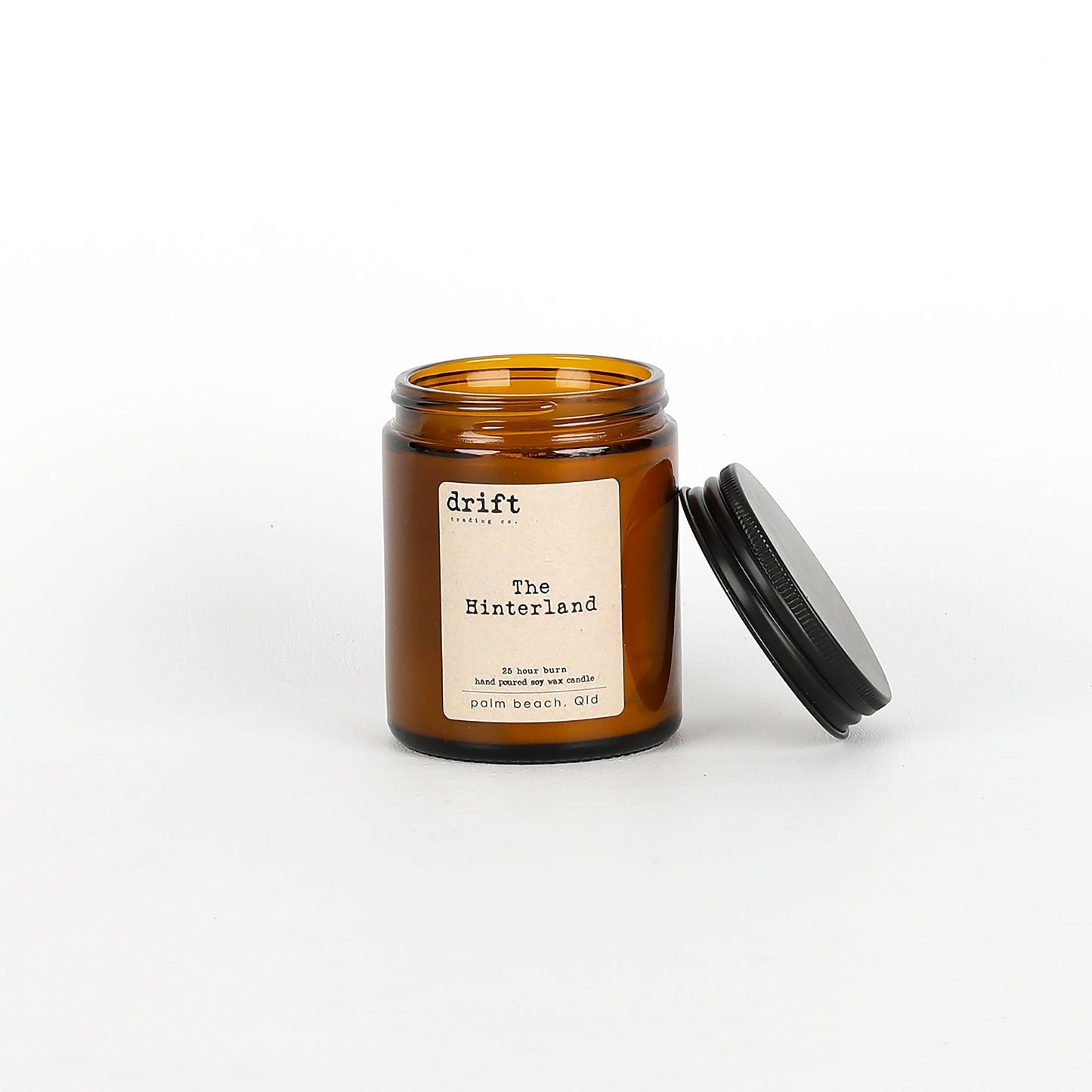 Amber glass candle jar with black lid on a white background