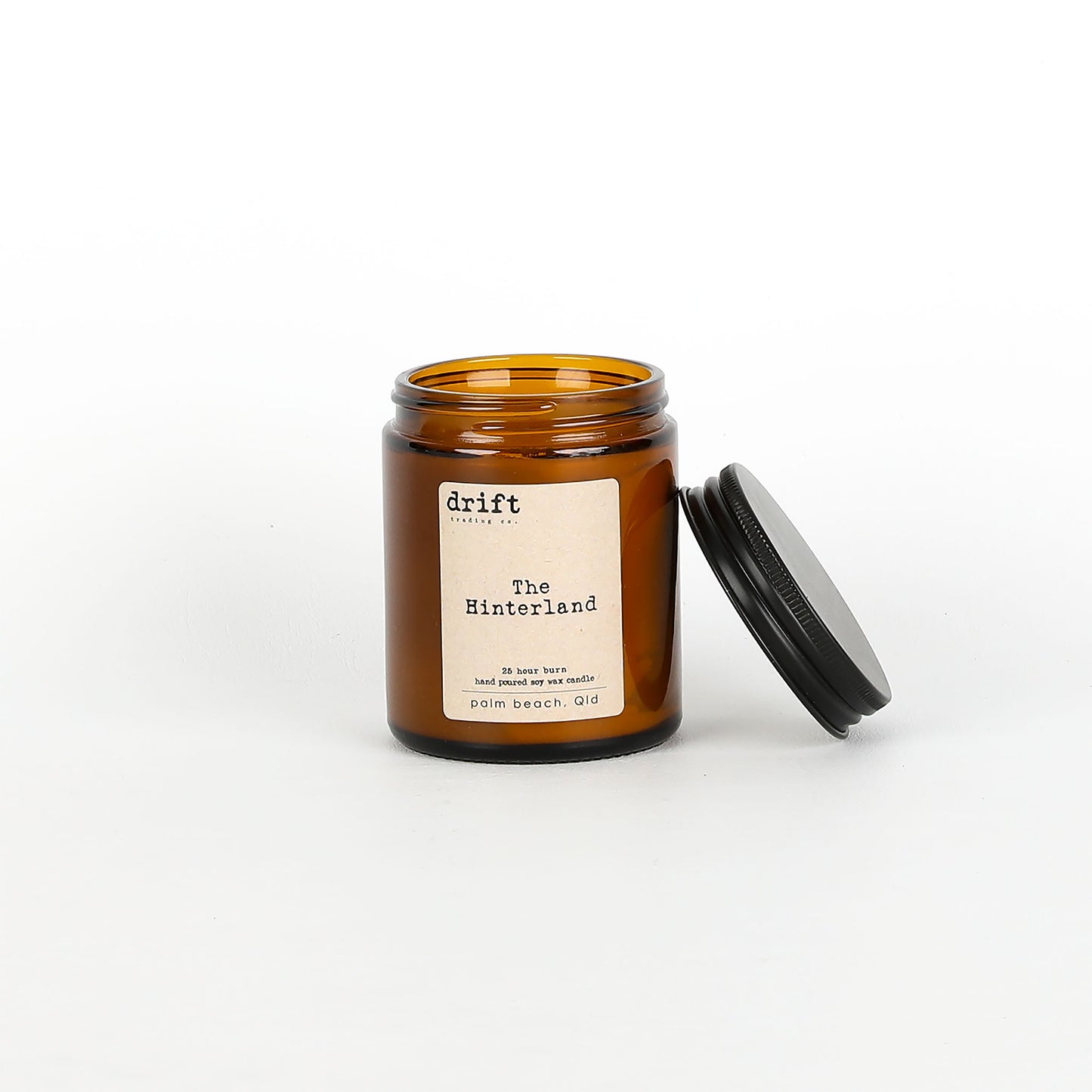 Amber glass candle jar with a black lid on a white background