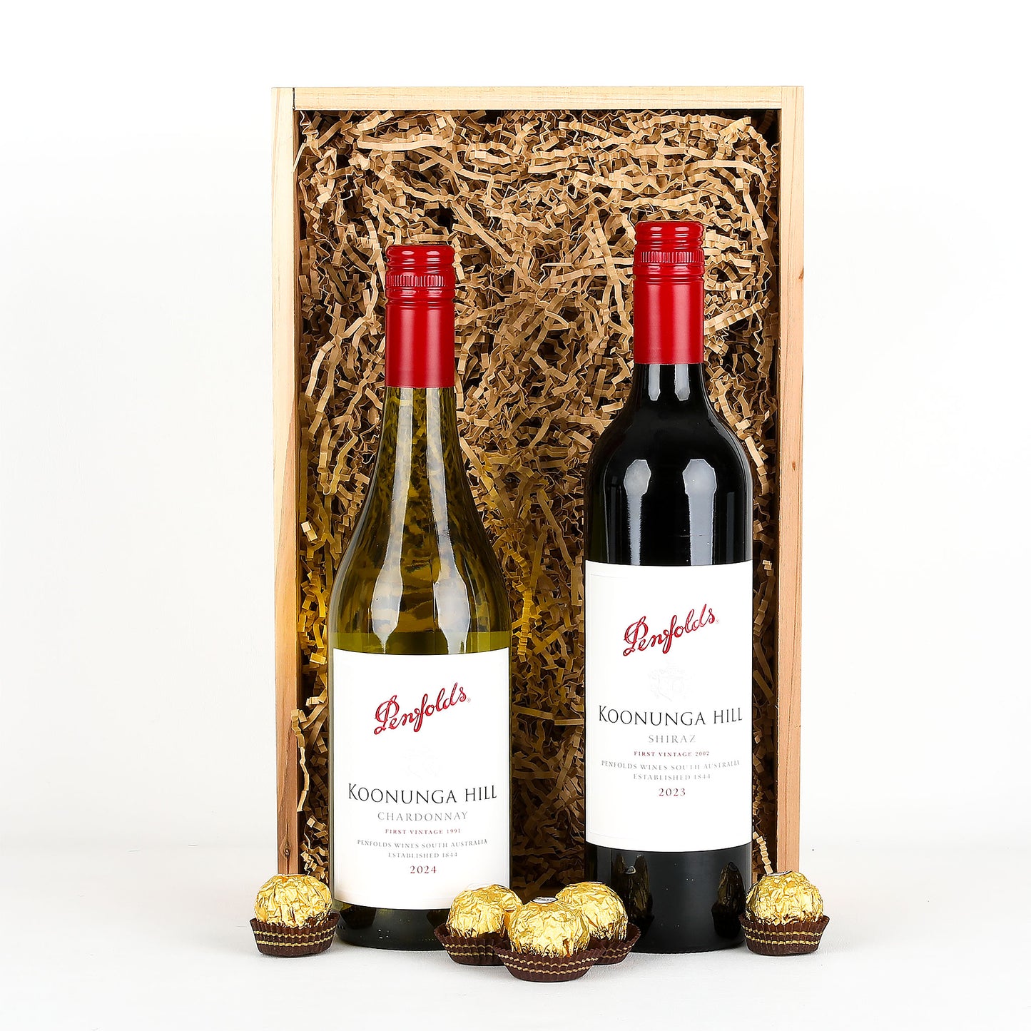 Two bottles of Penfolds Koonunga Hill wine in a wooden box with gold chocolates on a white background.