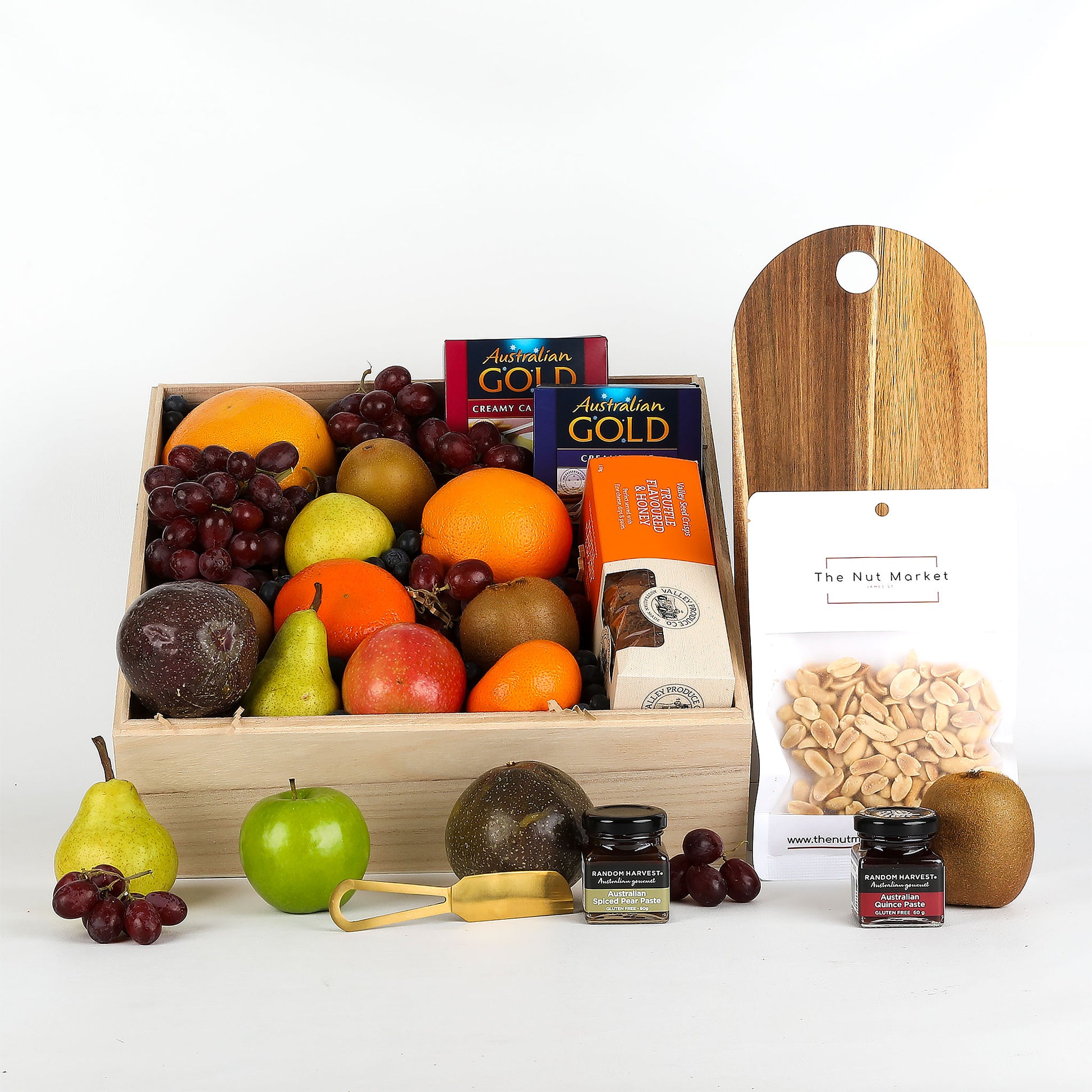 Fruit basket with assorted fruits, treats and cutting board on a white background.