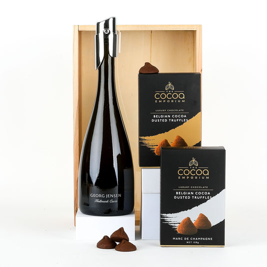 Bottle of Georg Jensen Hallmark Cuvée - a premium sparkling wine, with Belgian cocoa dusted triffles on a white background