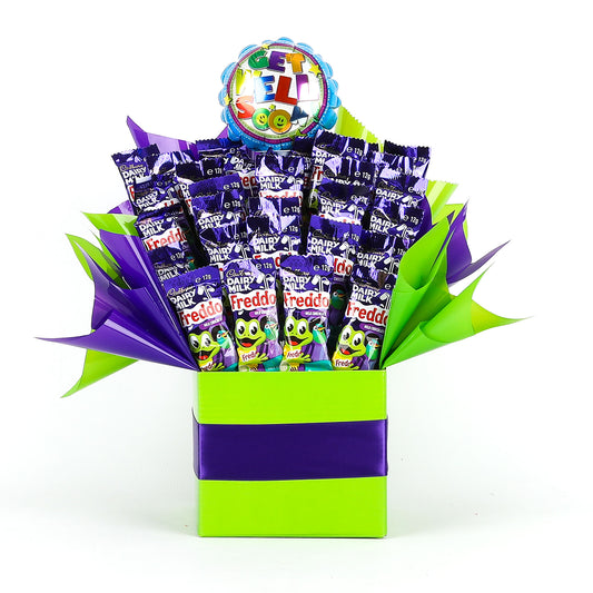 Colorful gift box filled with Cadbury Dairy Milk Freddo Frogs and a get well-themed balloon on a white background