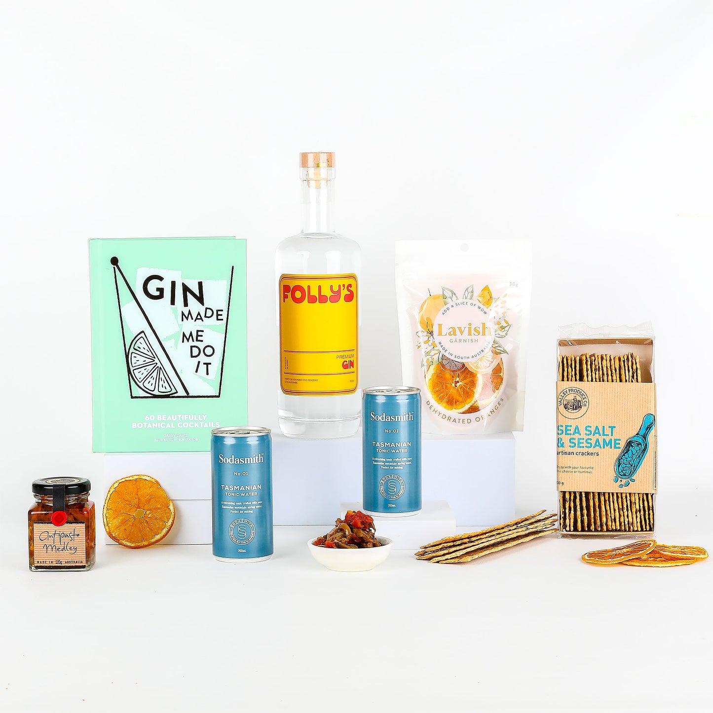 Folly’s Premium Gin, tonic water, recipe book & treats on a white background