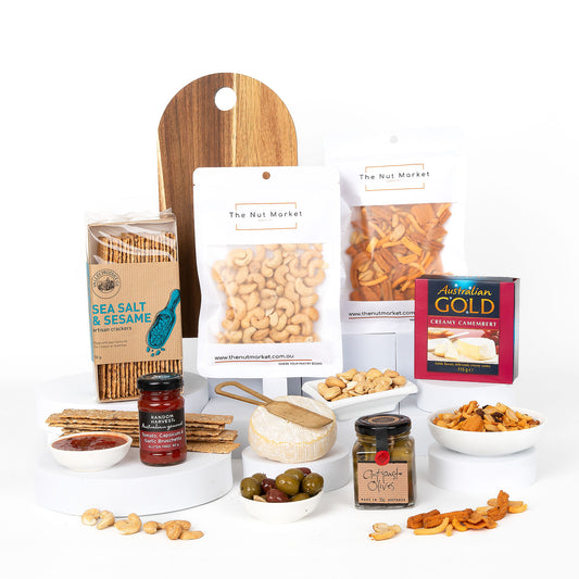 Gourmet gift basket with snacks, olives and other treats on a white background.