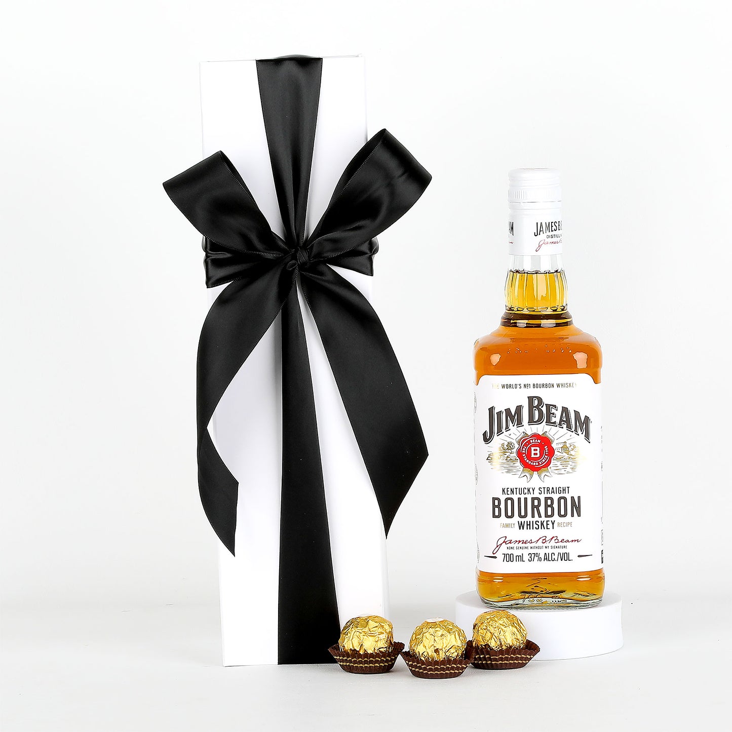 Jim Beam bourbon bottle with a black ribbon and Ferrero Rocher chocolates on a white background