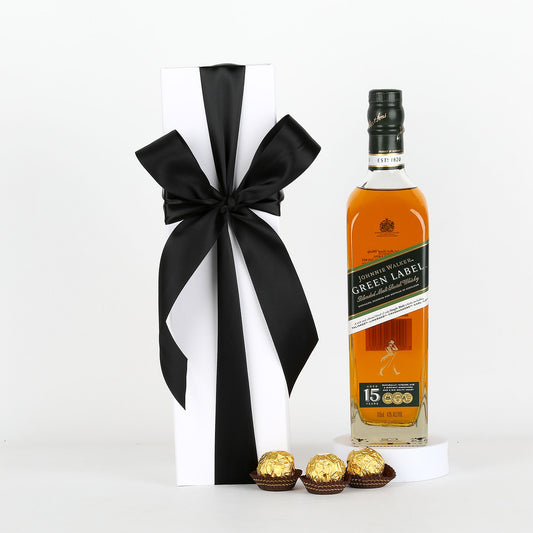 Johnnie Walker Green Label whisky bottle with a black ribbon and Ferrero Rocher chocolates on a white background