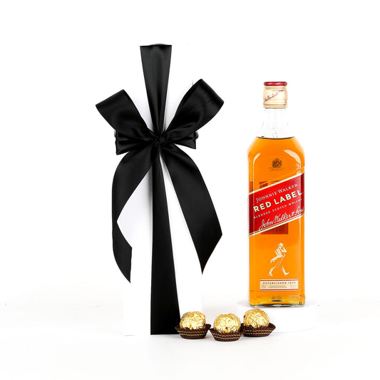Johnnie Walker Red Label whisky bottle with a black ribbon and Ferrero Rocher chocolates on a white background