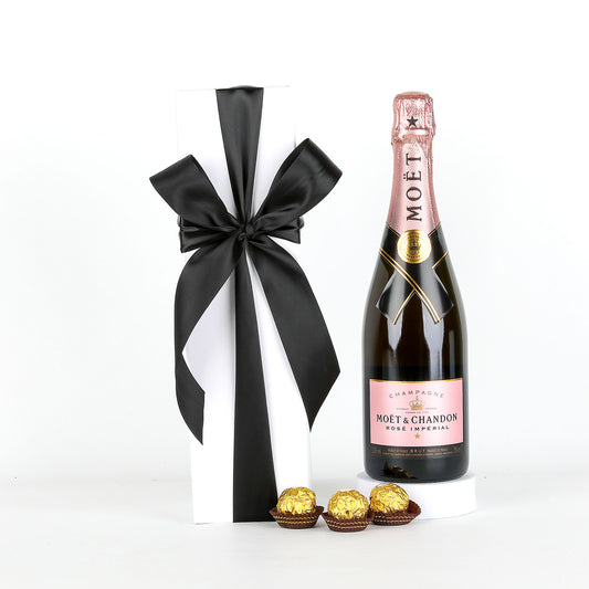 Bottle of Moët & Chandon champagne with a black ribbon and Ferrero Rocher chocolates on a white background