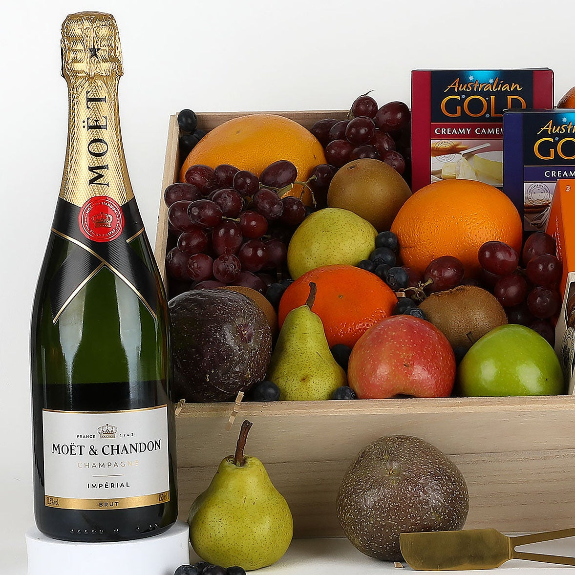 Gift basket with Moet champagne, fruits, and snacks on a white background
