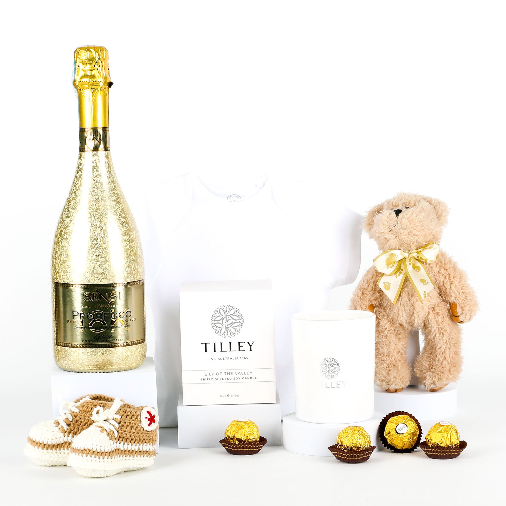 Bottle of Prosecco, teddy bear, and chocolates on a white background