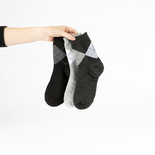 Hand holding three black and grey socks against a white background