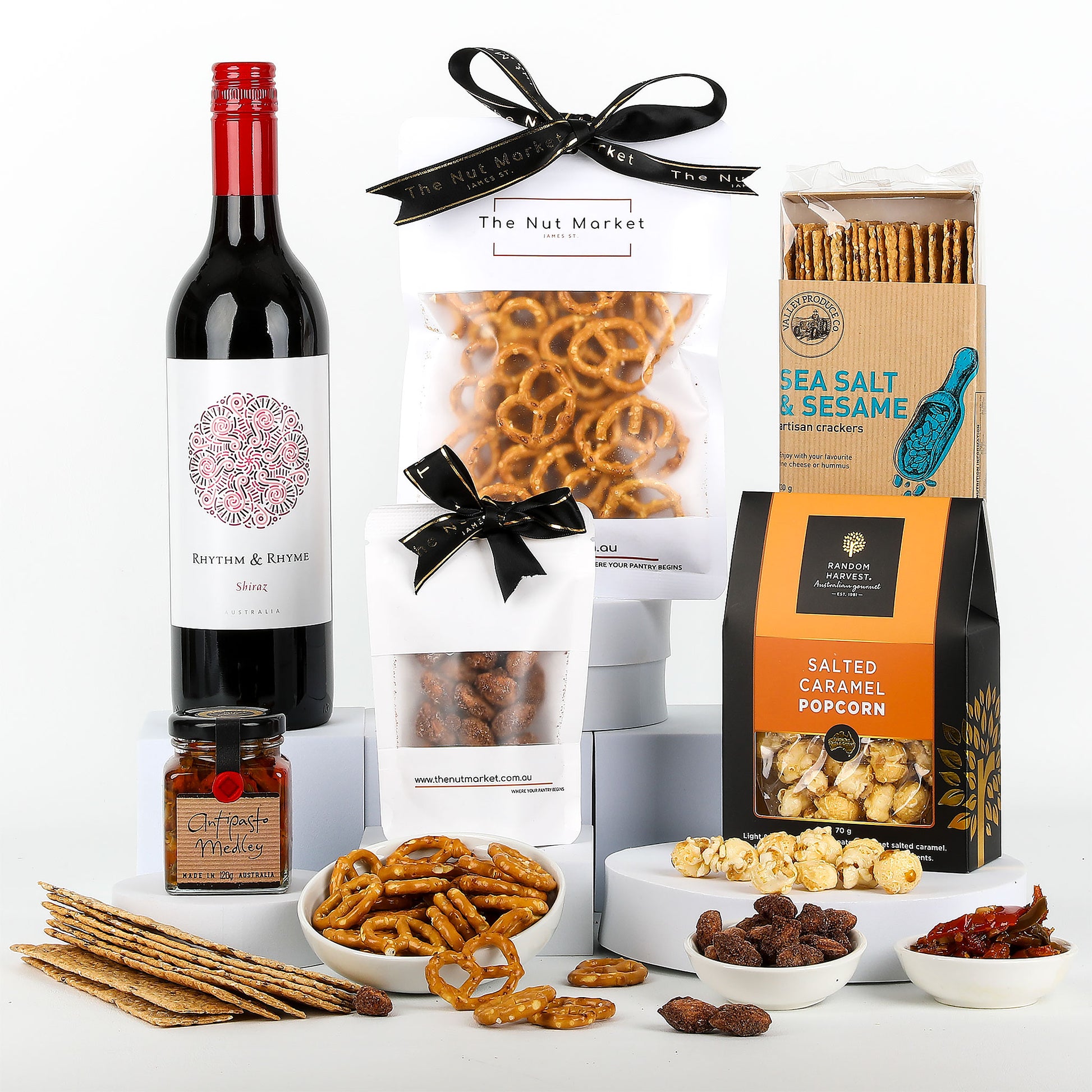Gourmet gift set with wine, pretzels, and various snacks on a white background