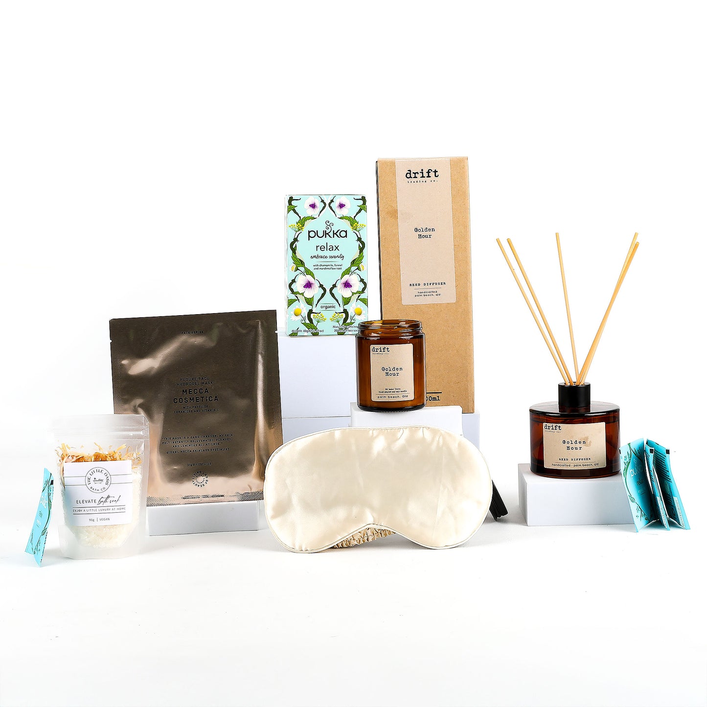 Collection of wellness products including a sleep mask, candle, and diffuser on a white background