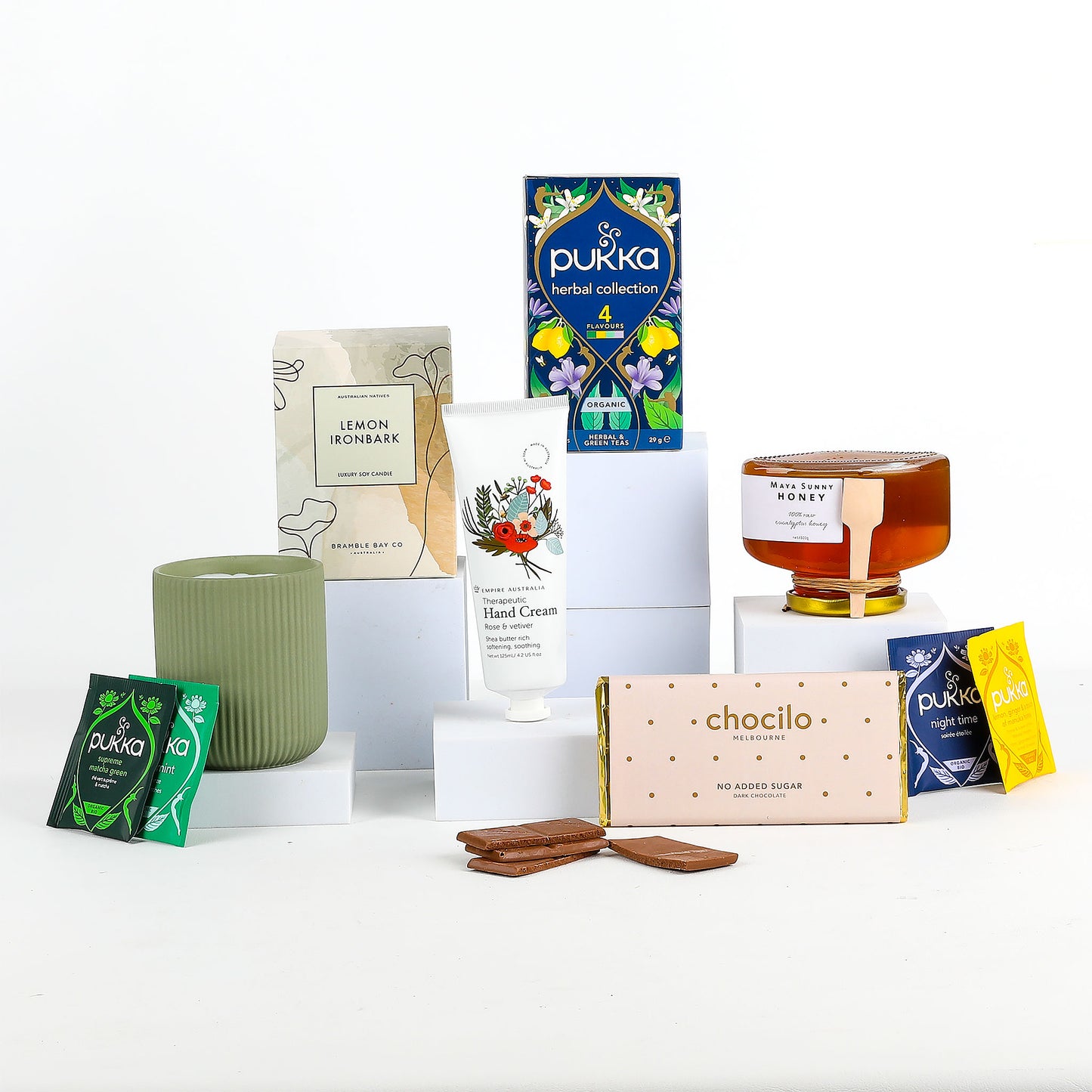 Collection of Pukka tea box, a candle, hand cream, and other products on a white background